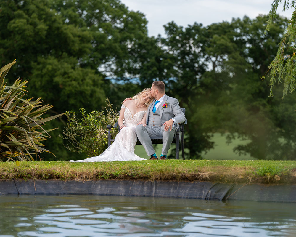 Bride and Groom on bench by the lake.