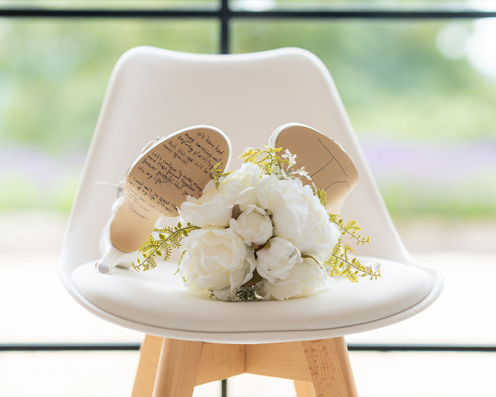 Wedding shoes and flowers on a white chair.