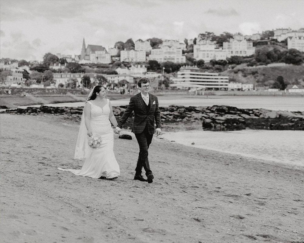 Bride and Groom walking along the beach at Torquay, Devon.