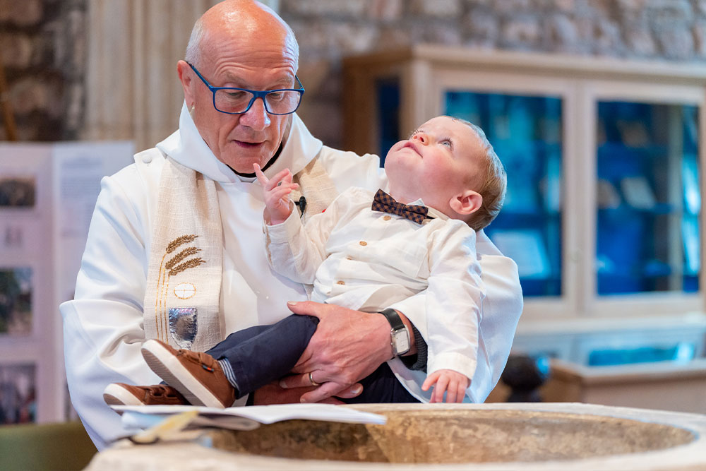 Vicar Christening child, looking up to God.