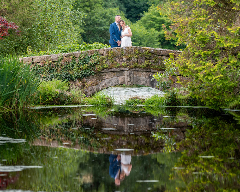 Bride and Groom on bridge by lake at Bovey Castle.