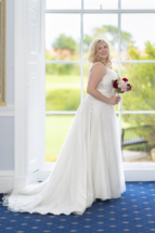 Bride by window at Exeter golf and country club.