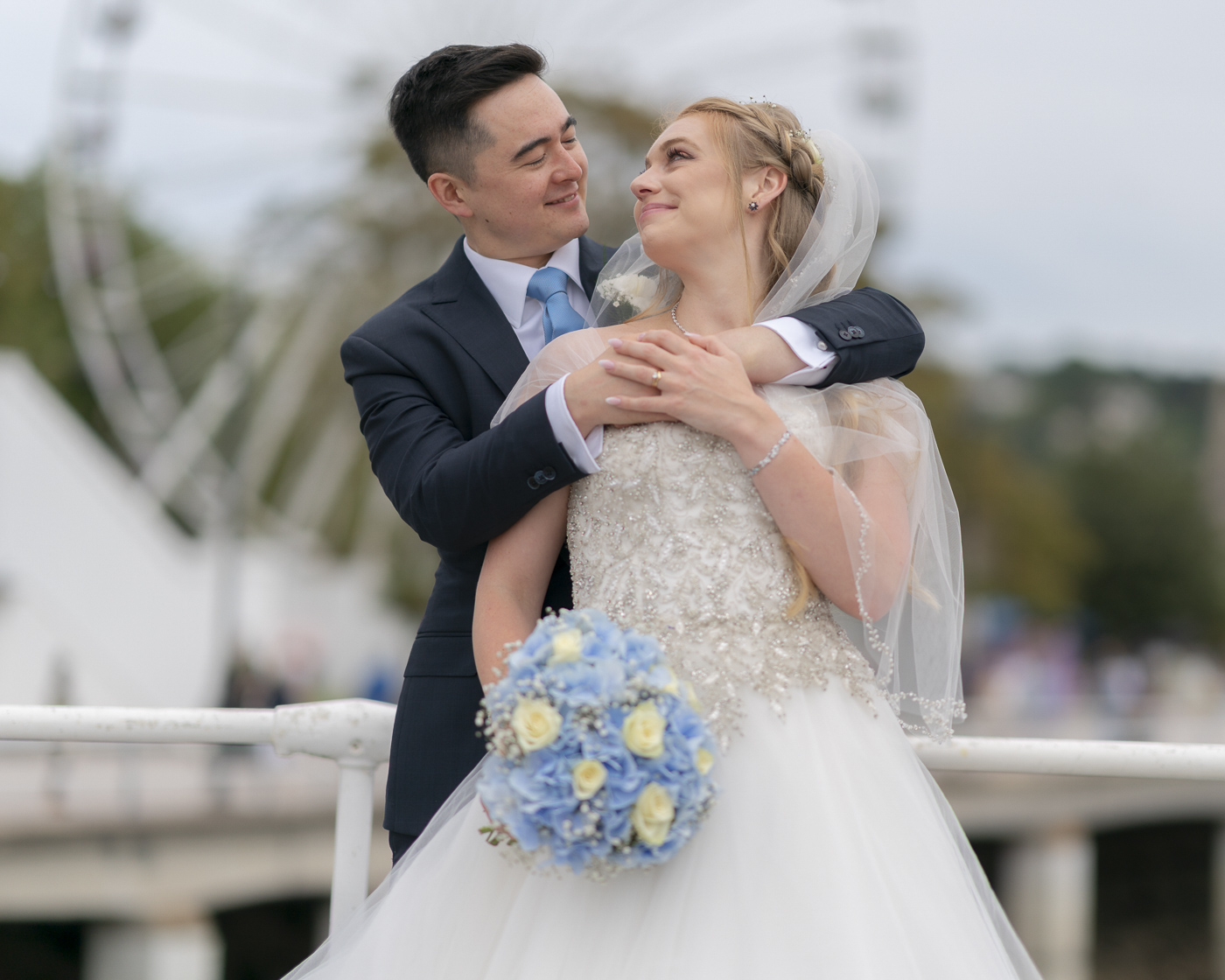 Bride and Groom on Torquay pier with big wheel in the background.